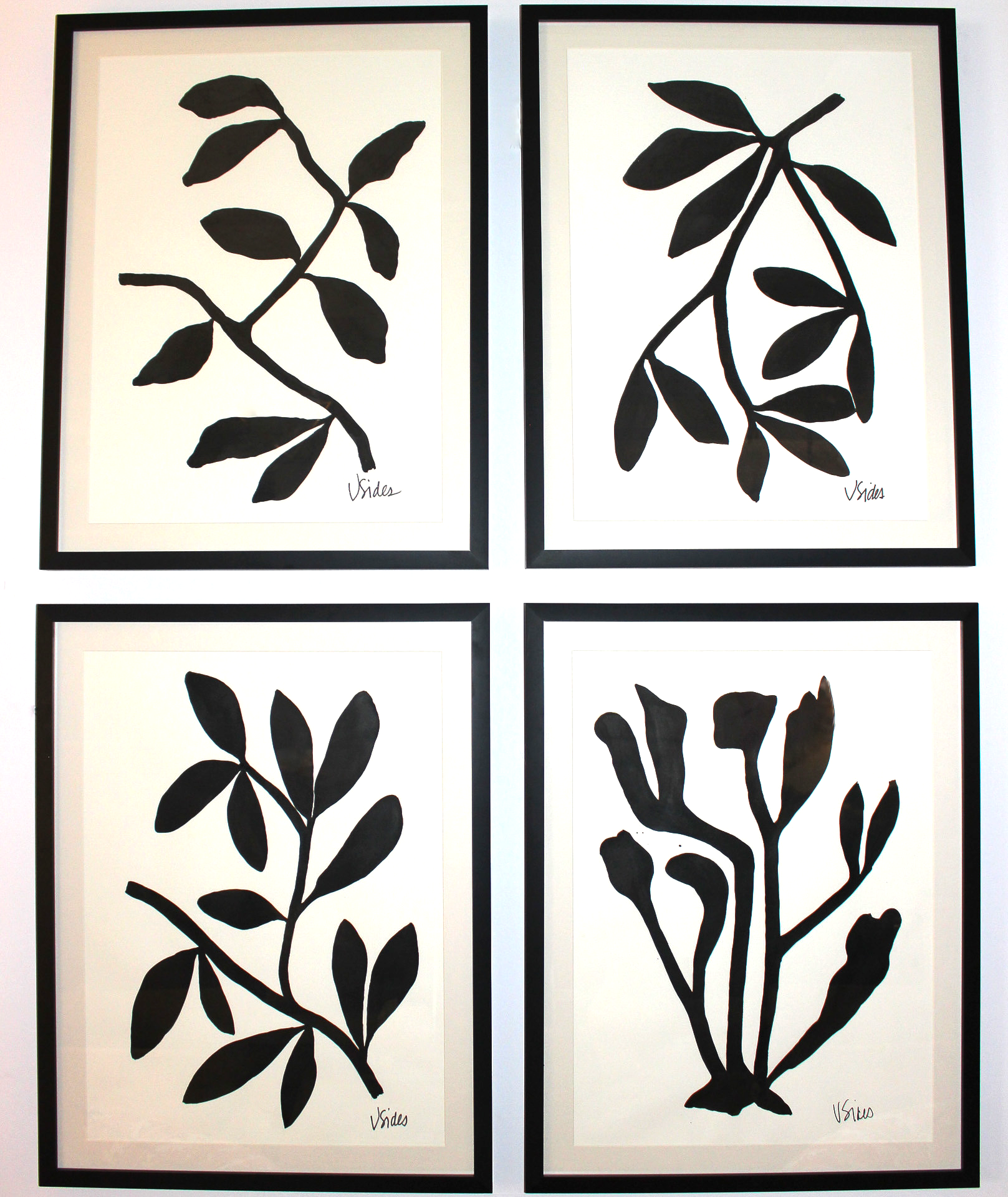 Four black and white wall art prints of leaf designs on a light background.