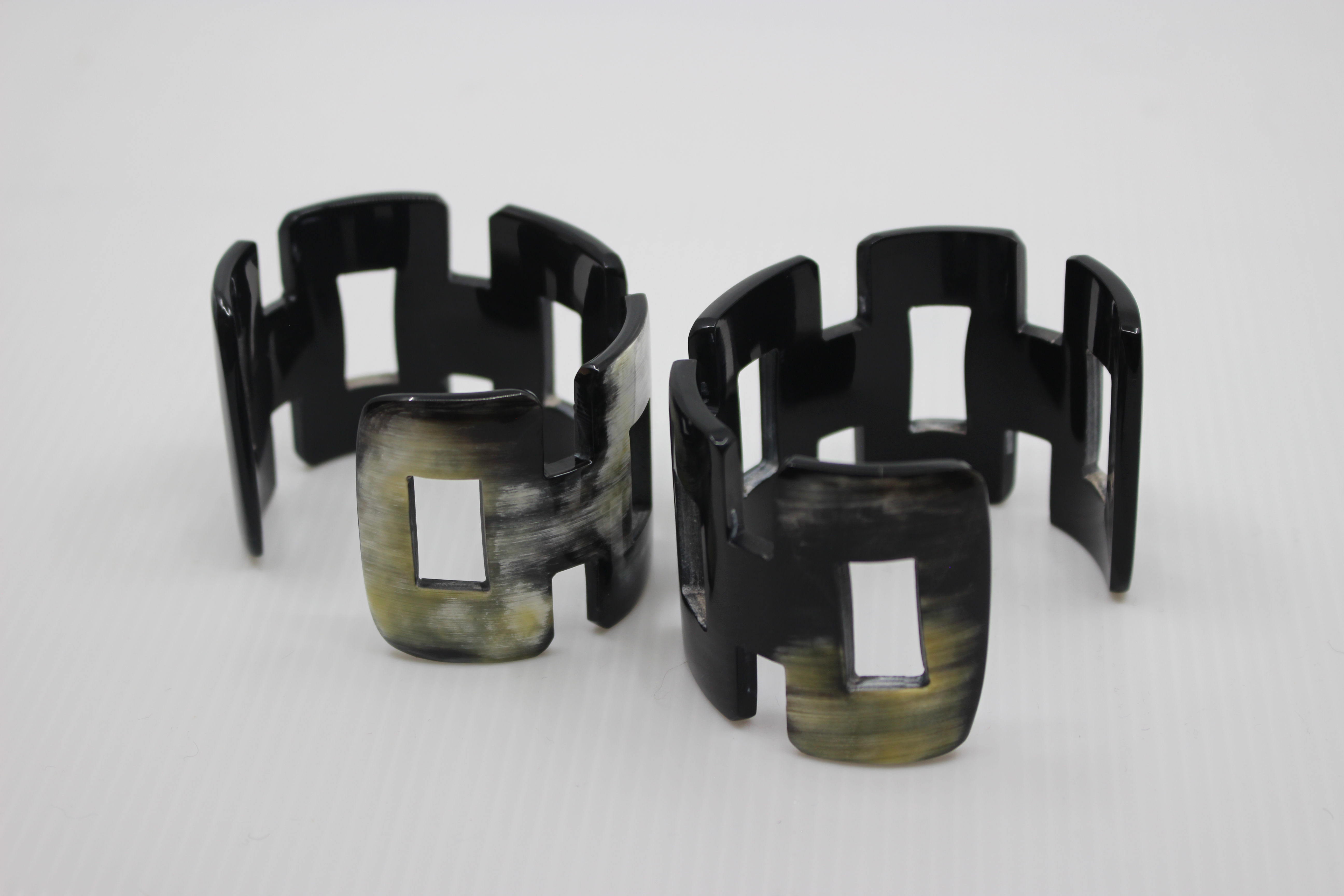 Set of black and green geometric cuff bracelets on a white background