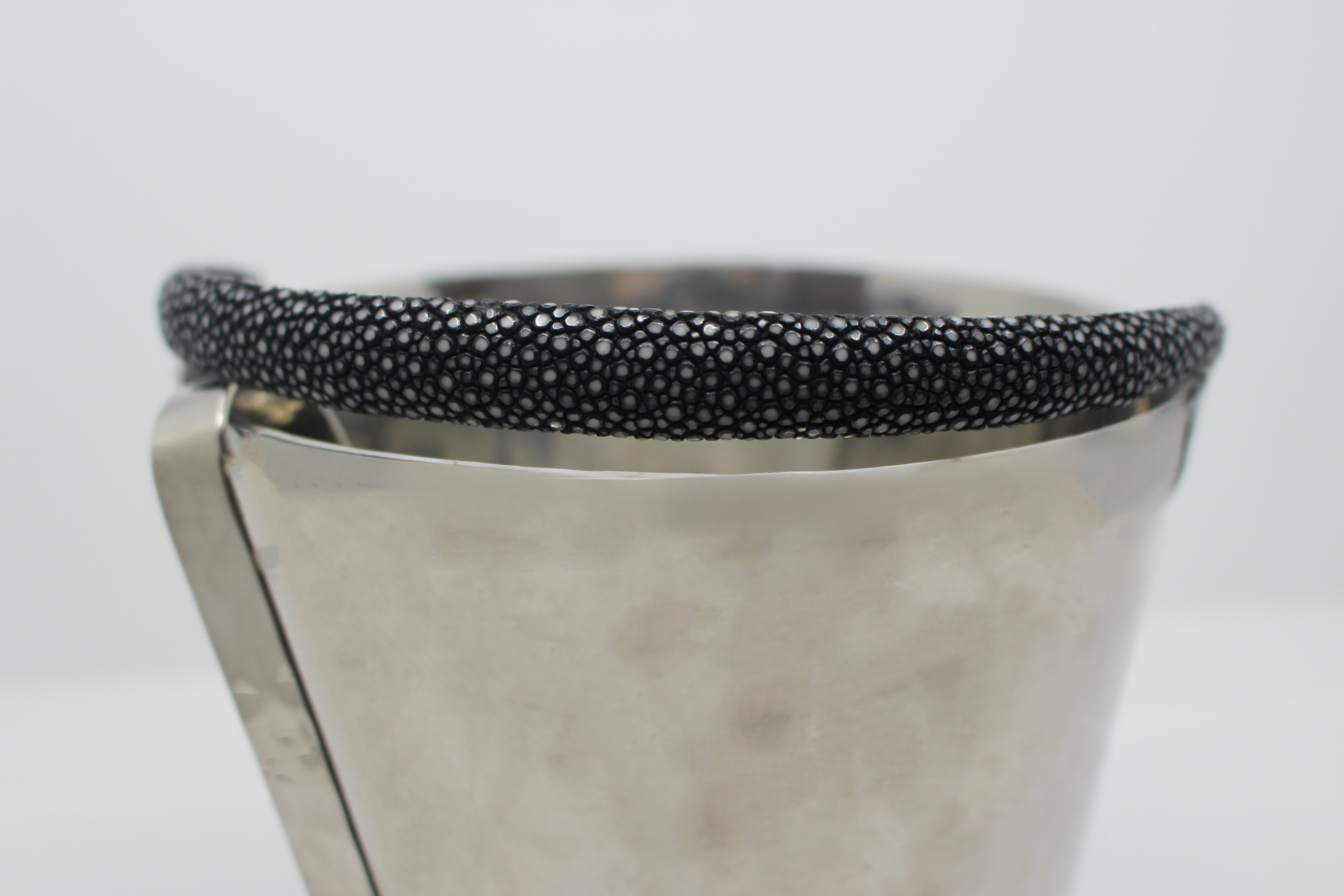Metallic ice bucket with black textured rim on a light gray background