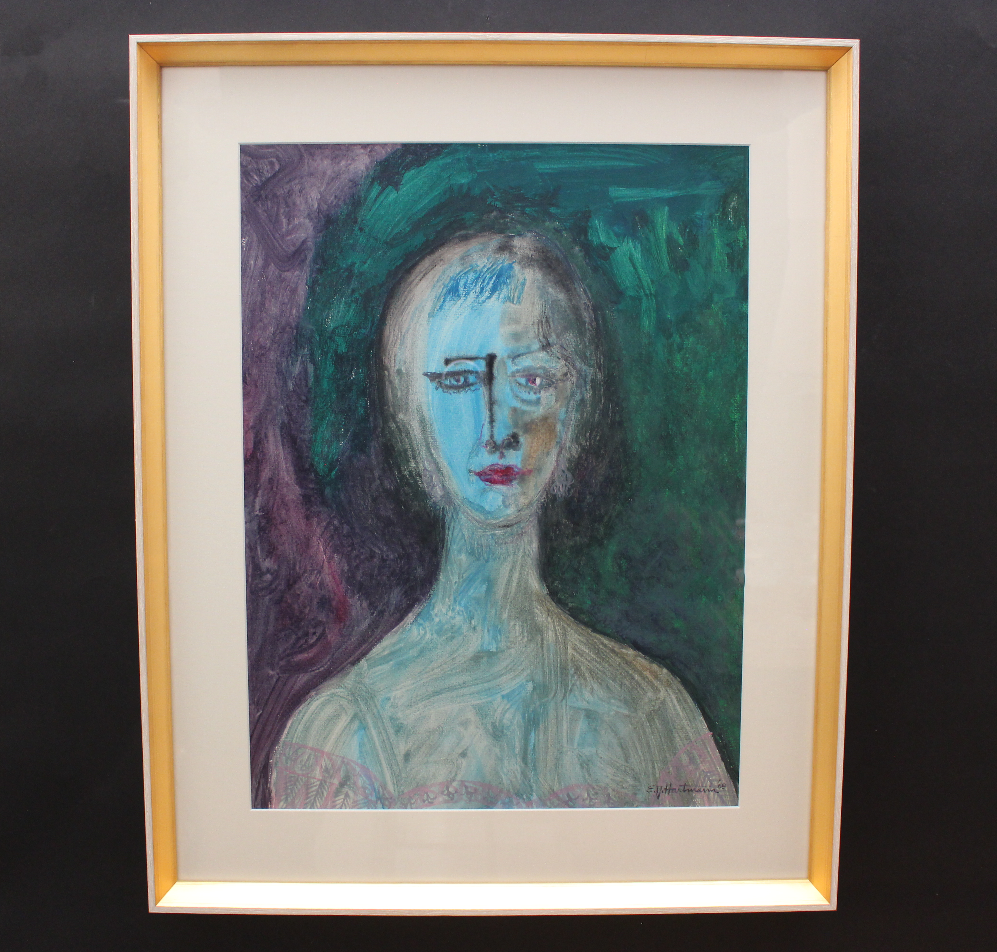Framed abstract painting of a face with a gold frame on a black background