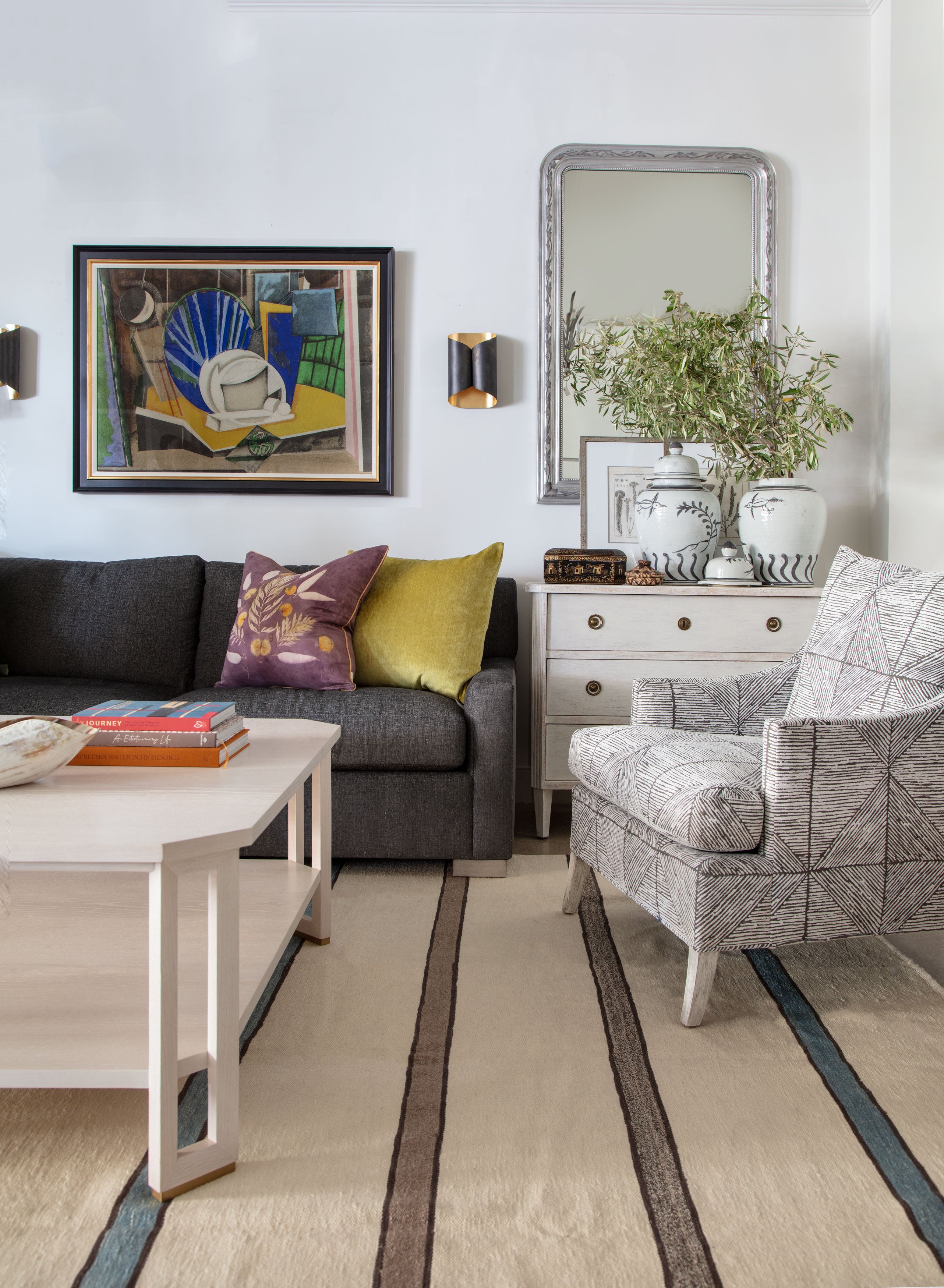 living room setting with grey sofa, striped rug, brown and white chair and white cocktail table