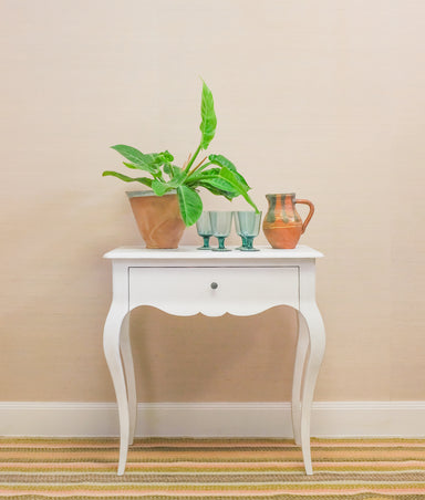 white side table with striped rug and accessories on top