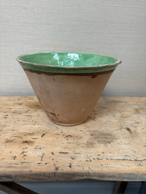 Vintage ceramic planter with green top and brown base on a wooden table.