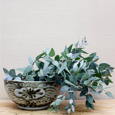 large pottery bowl with bold painted design filled with eucalyptus