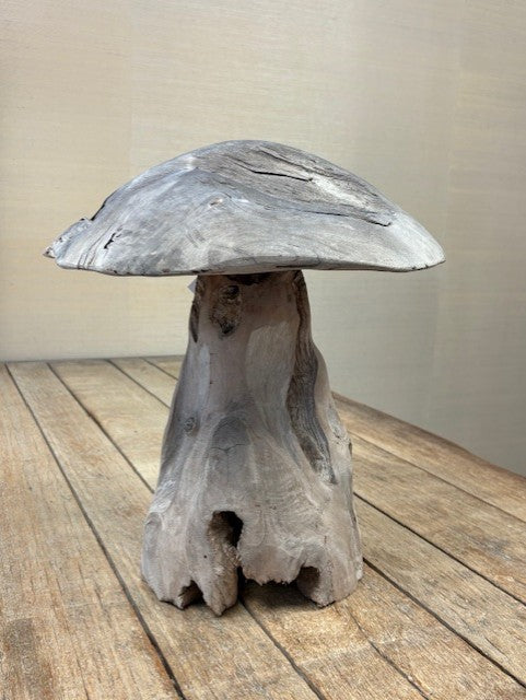 Mushroom-shaped stone sculpture on a wooden surface with a plain background
