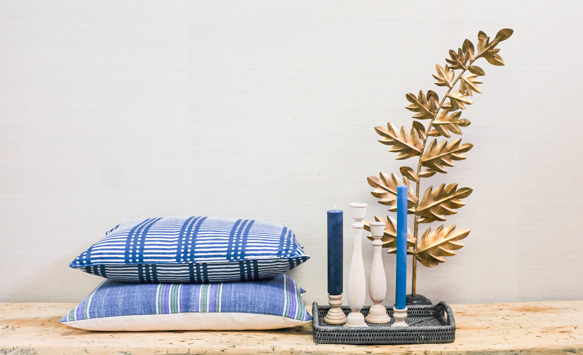 stacked pillows with tray of accessories including candlesticks and candles