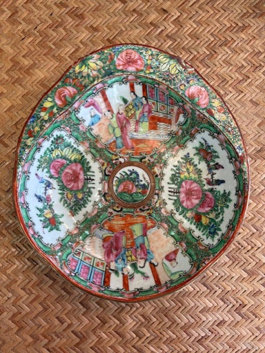 Decorative shrimp bowl with colorful floral and figurine design on a woven surface
