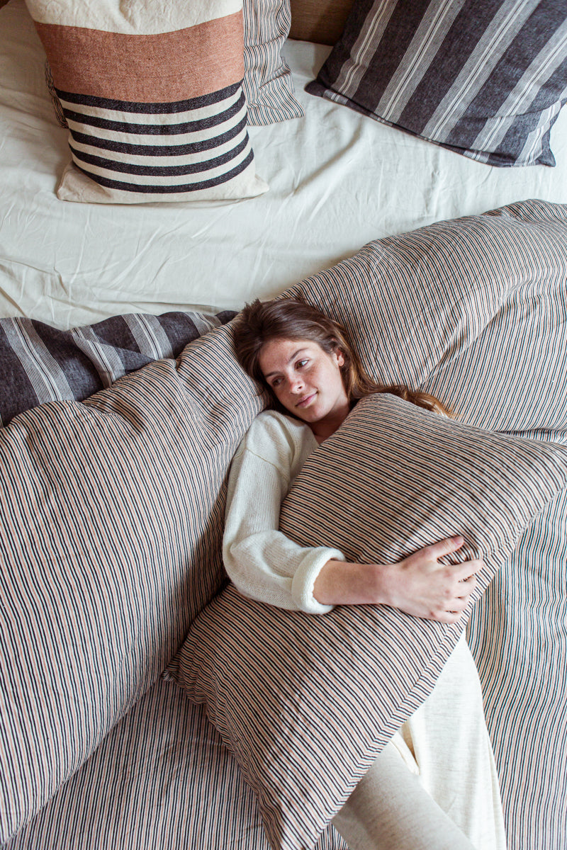 woman on bed with striped linens