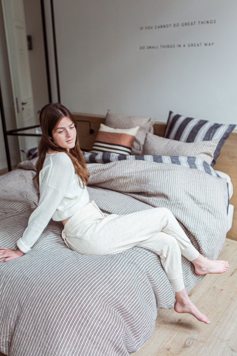 woman sitting on bed dressed in striped linens