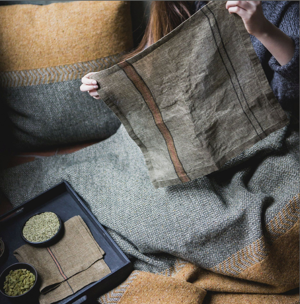 Bronzy-green linen napkin Marie from Libeco shown with bedding and pillow