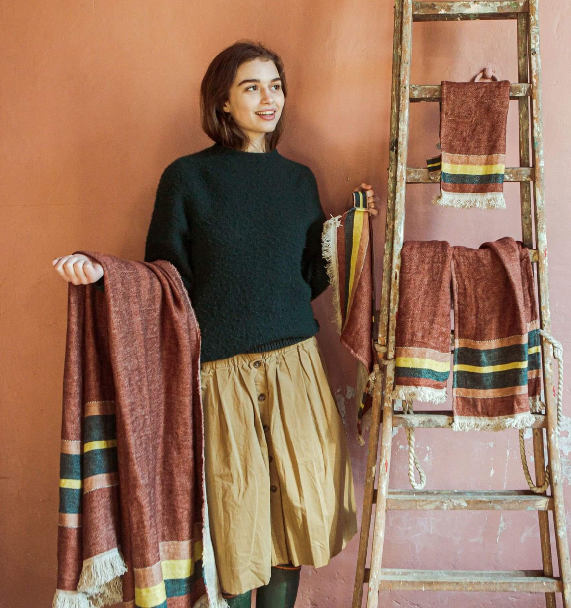 woman showing off the range of linen towel sizes for the old rose color