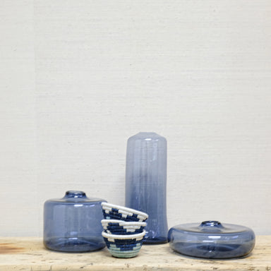 transparent blue glass bottles and stack of blue and white grass baskets