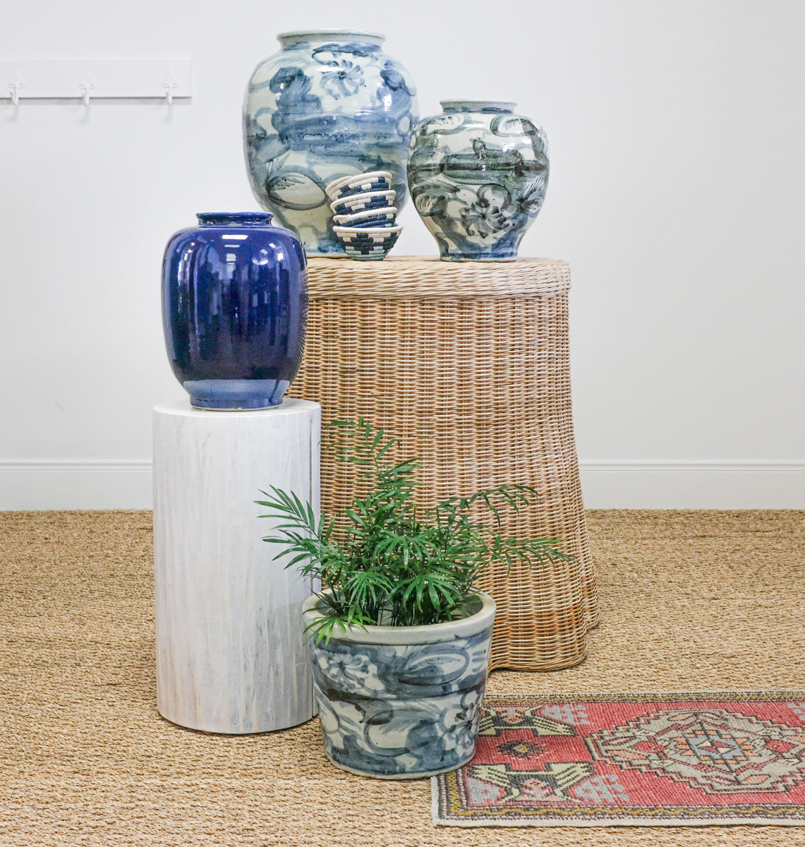 blue and white pottery on wicker table with small red rug