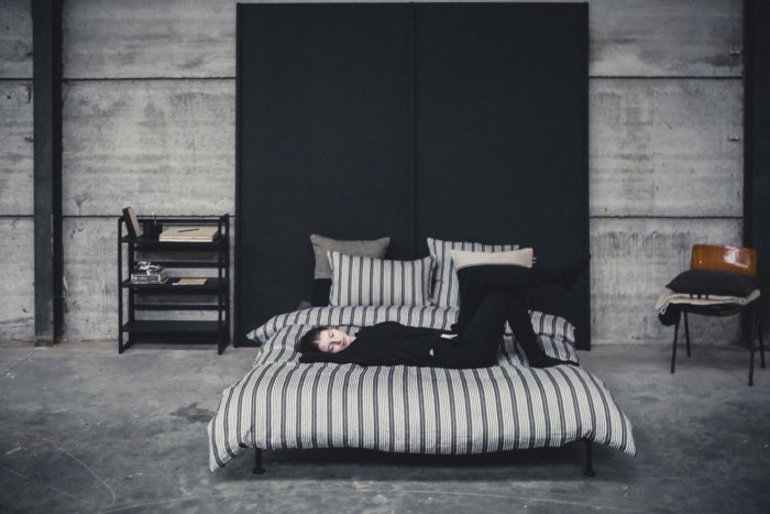 woman reclining on bed show black and ivory striped bedding