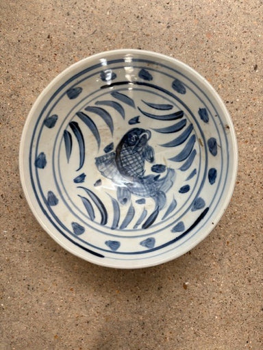 Ceramic bowl with blue fish design on a beige surface