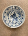 Ceramic bowl with blue fish design on a beige surface