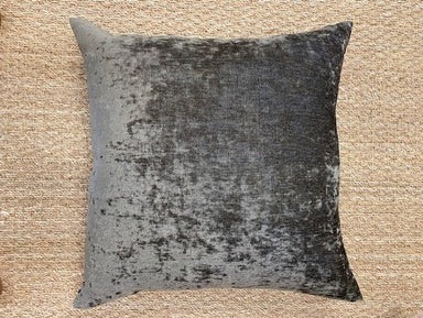 Textured dark brown pillow on a beige woven surface