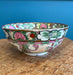 Decorative ceramic bowl with colorful floral and animal patterns on a woven surface with blue background