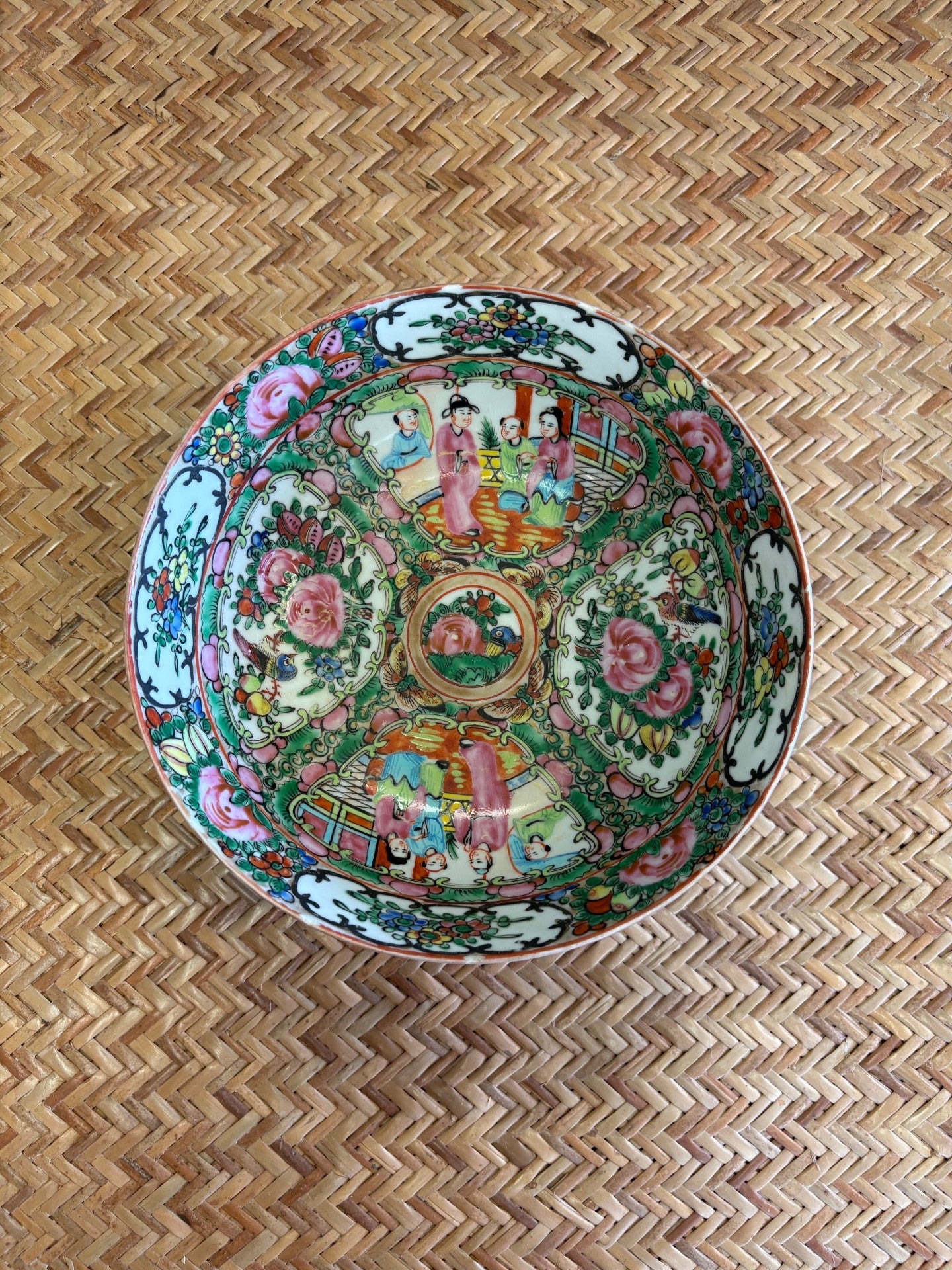Decorative ceramic plate with colorful patterns on a woven surface