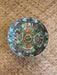 Decorative ceramic plate with colorful patterns on a woven surface
