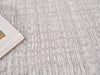 Close-up of a textured neutral carpet with a corner of a white frame visible.