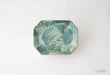 Hexagonal ceramic dish with green marbled pattern on a white background