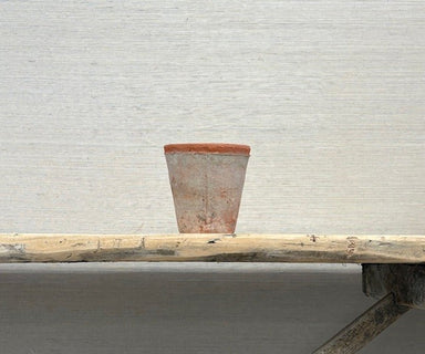 Terracotta pot on a wooden bench against a textured wall