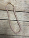 A single strand of pale pink faceted beads with a knotted tan cord, laid on a rustic weathered wood surface.