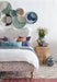 upholstered bed with wicker side table, striped pillows, baskets and blue and white pottery