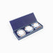 A navy blue gift box with a striped border, open to reveal three round frames with blue and orange marble patterns and white labels, set against a plain white background.