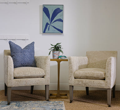pair of upholstered chairs in velvet with small gold side table between
