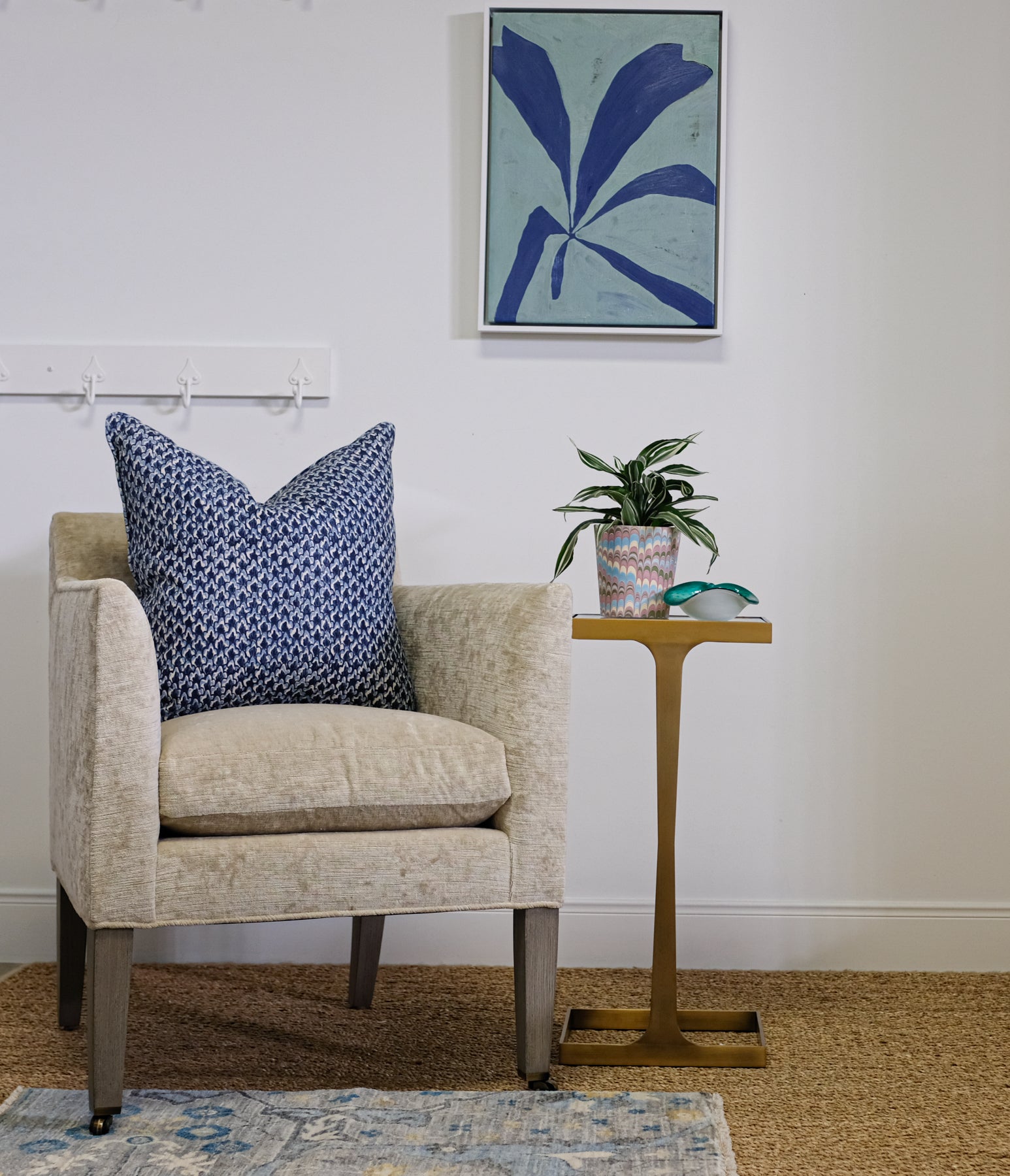 velvet chair shown with side table, blue pillow and rug, and graphic blue canvas artwork