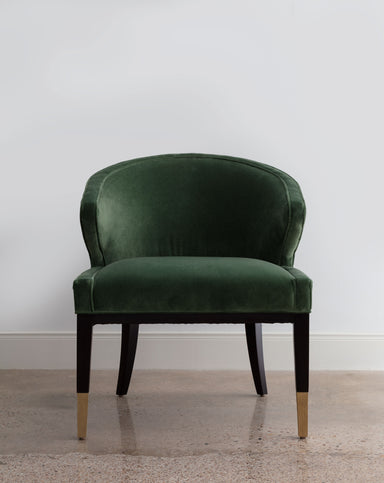 green velvet chair with dark legs and brass accents