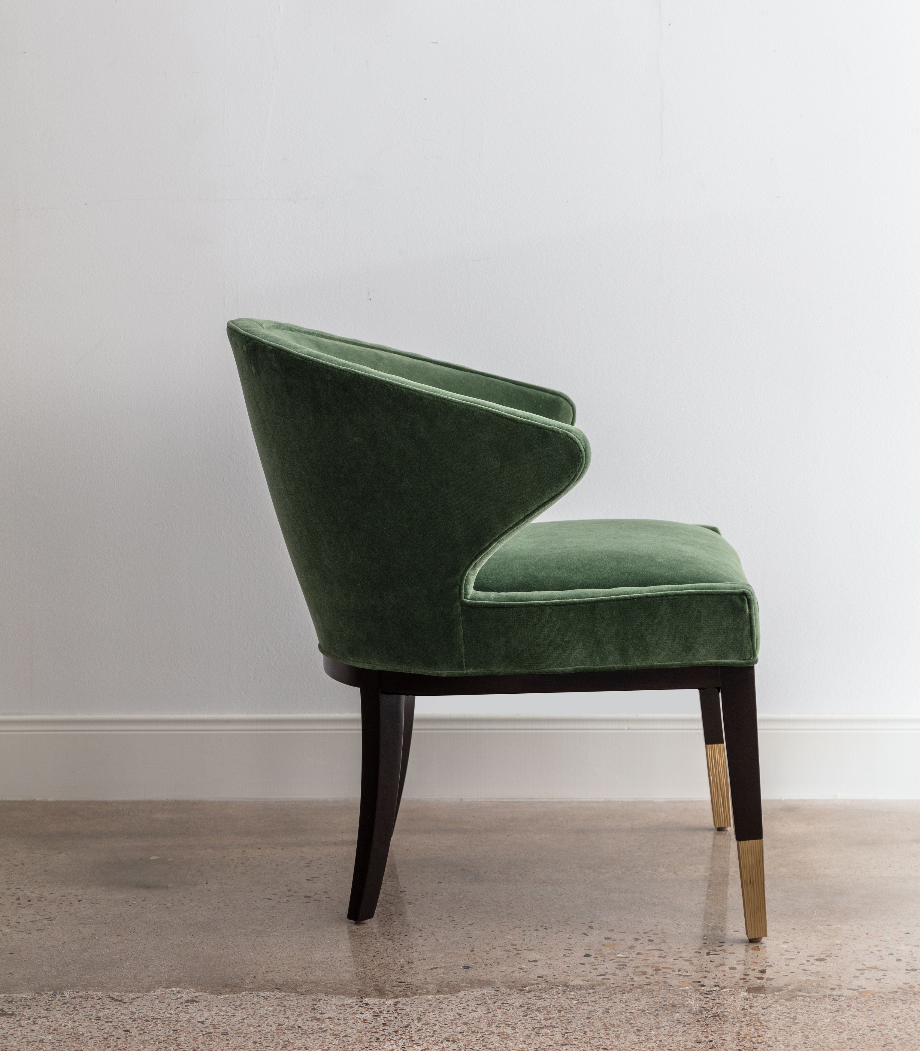side view of green velvet chair with rounded back