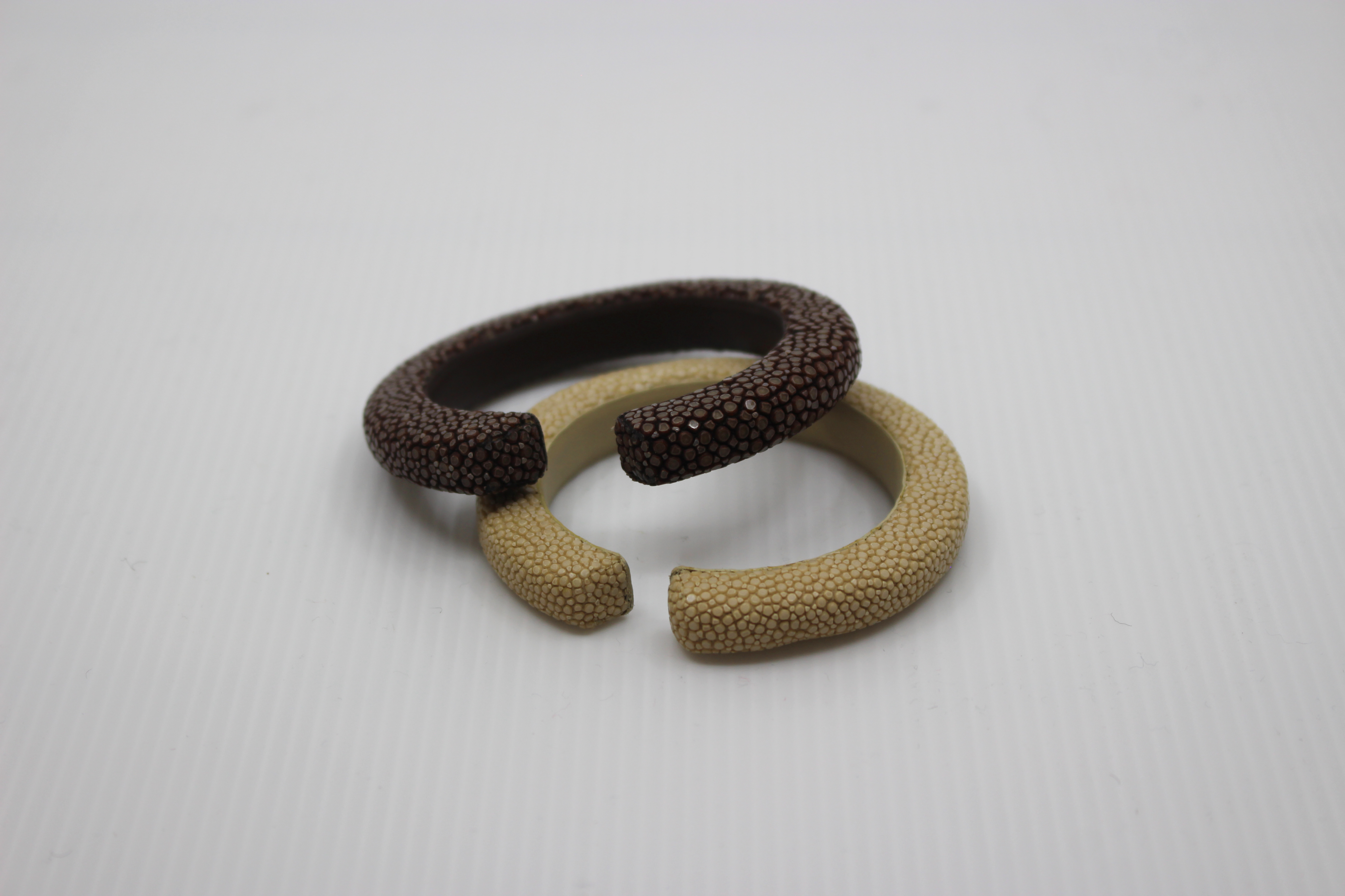 Two textured hairbands, one brown and one beige, on a light gray background.