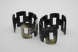 Set of black and green geometric cuff bracelets on a white background