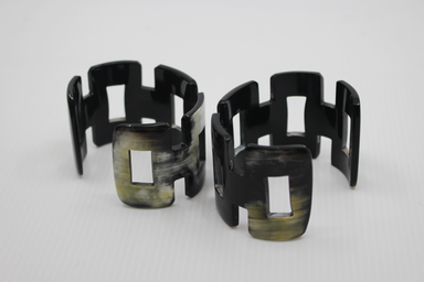 Set of black and green geometric cuff bracelets on a white background