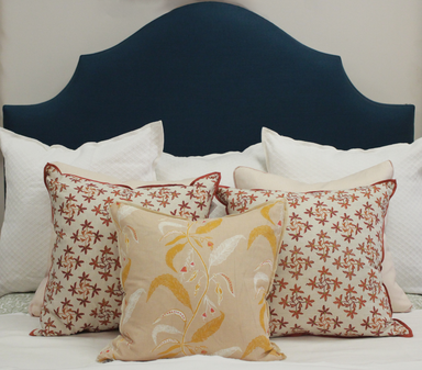 Decorative pillows with floral patterns on a bed with a blue headboard.