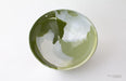 Green ceramic bowl with white interior on a white background