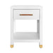A modern white nightstand with a single drawer, open lower shelf, and small gold-toned legs and handle, shown on a plain white background.