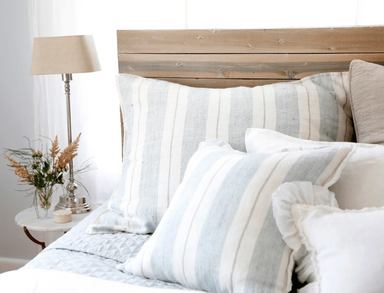 natural and blue pillows on bed with wood headboard