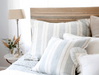 natural and blue pillows on bed with wood headboard