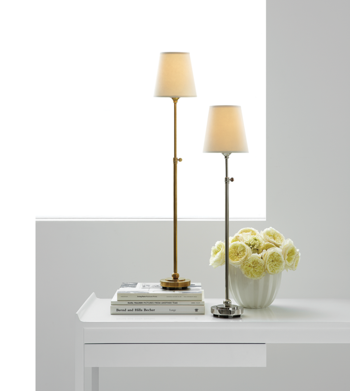 stick-style brass and nickel lamps on white console table