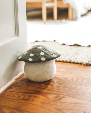 felted mushroom doorstop on floor by white door