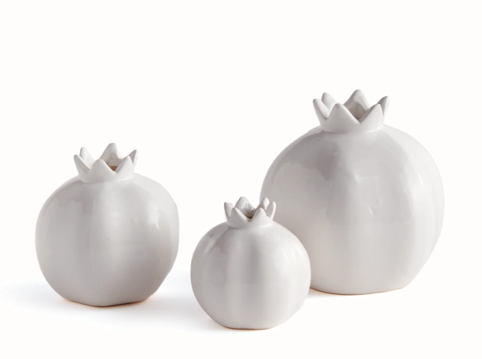 Three glossy white ceramic pomegranate-shaped decorative vases of different sizes, arranged on a seamless white background.