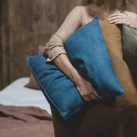 a woman holding several pillows