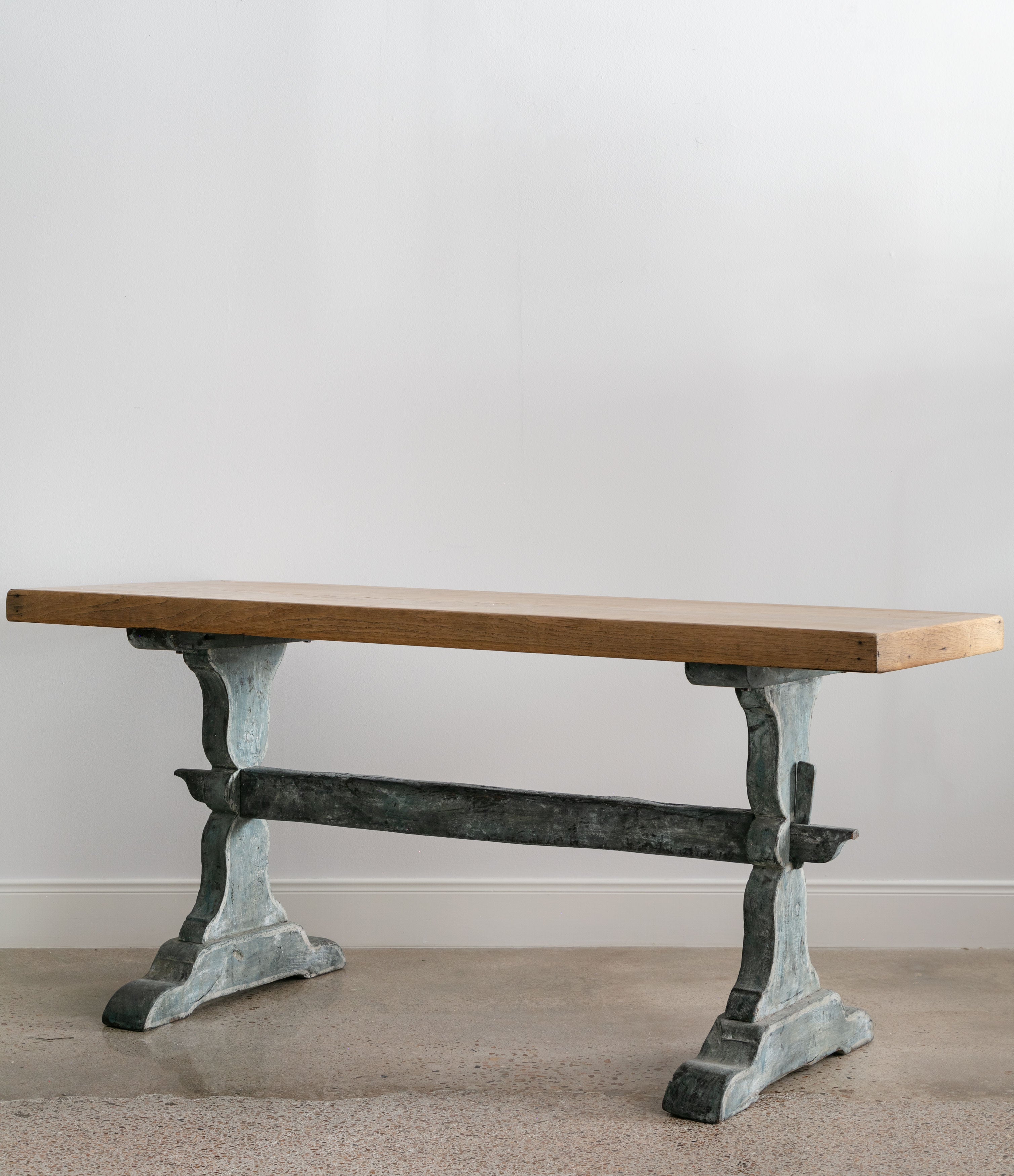 angled view of antique trestle table with blue base