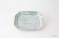 An octagonal ceramic plate with a textured, organic pattern in pale aqua and white glaze, set against a plain white background.