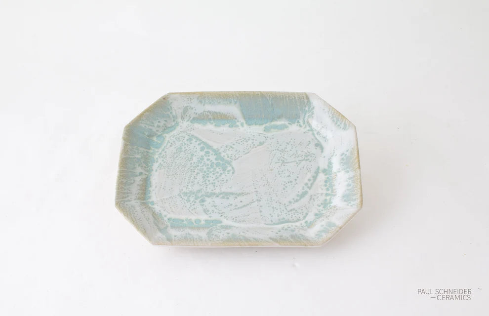 An octagonal ceramic plate with a textured, organic pattern in pale aqua and white glaze, set against a plain white background.