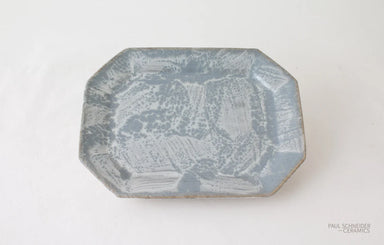 An octagonal ceramic plate with a textured, mottled blue and white glaze, photographed from a top-down angle on a white background.